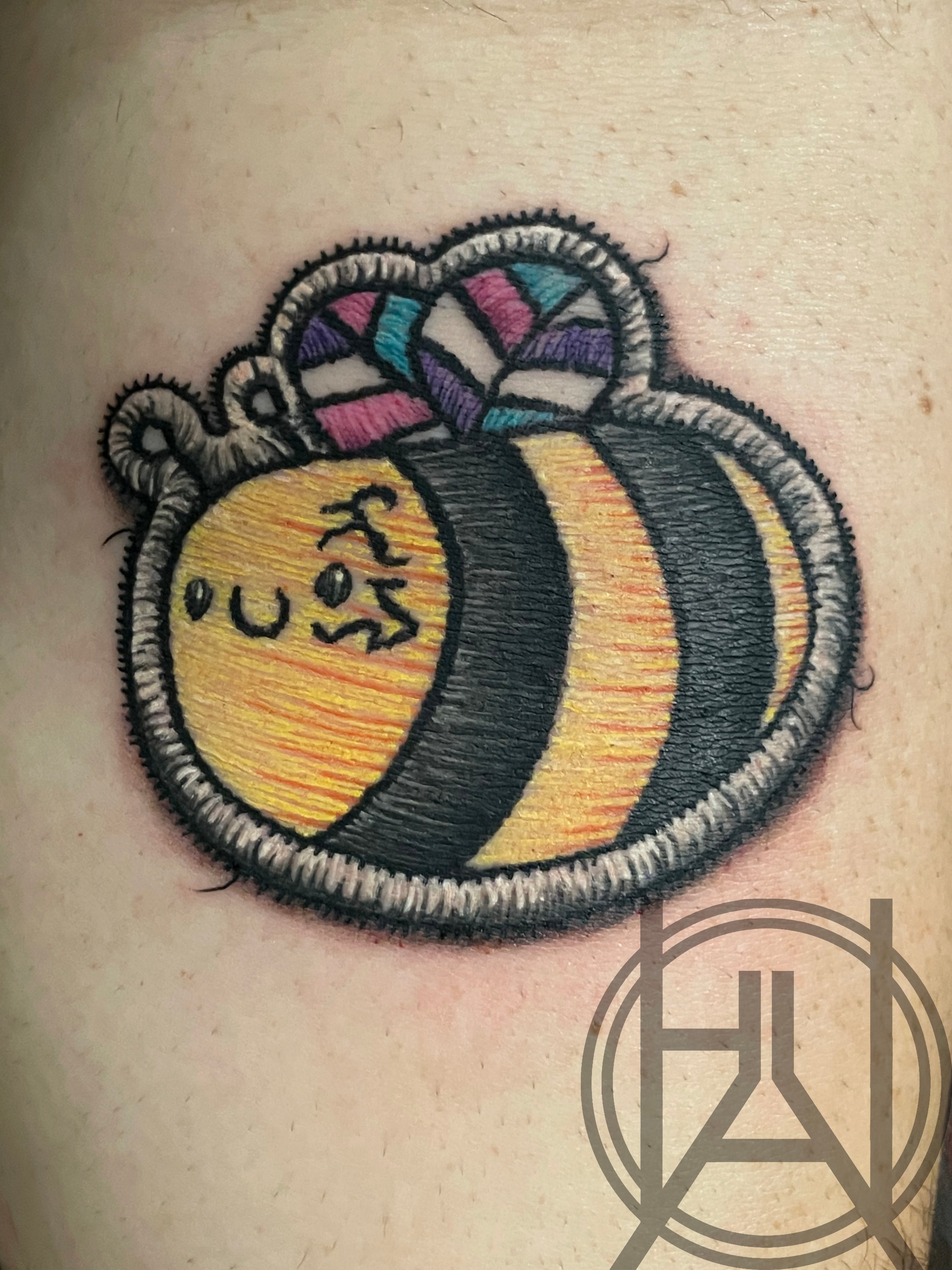 Embroidery-style bumblebee patch with pride flag wings — color