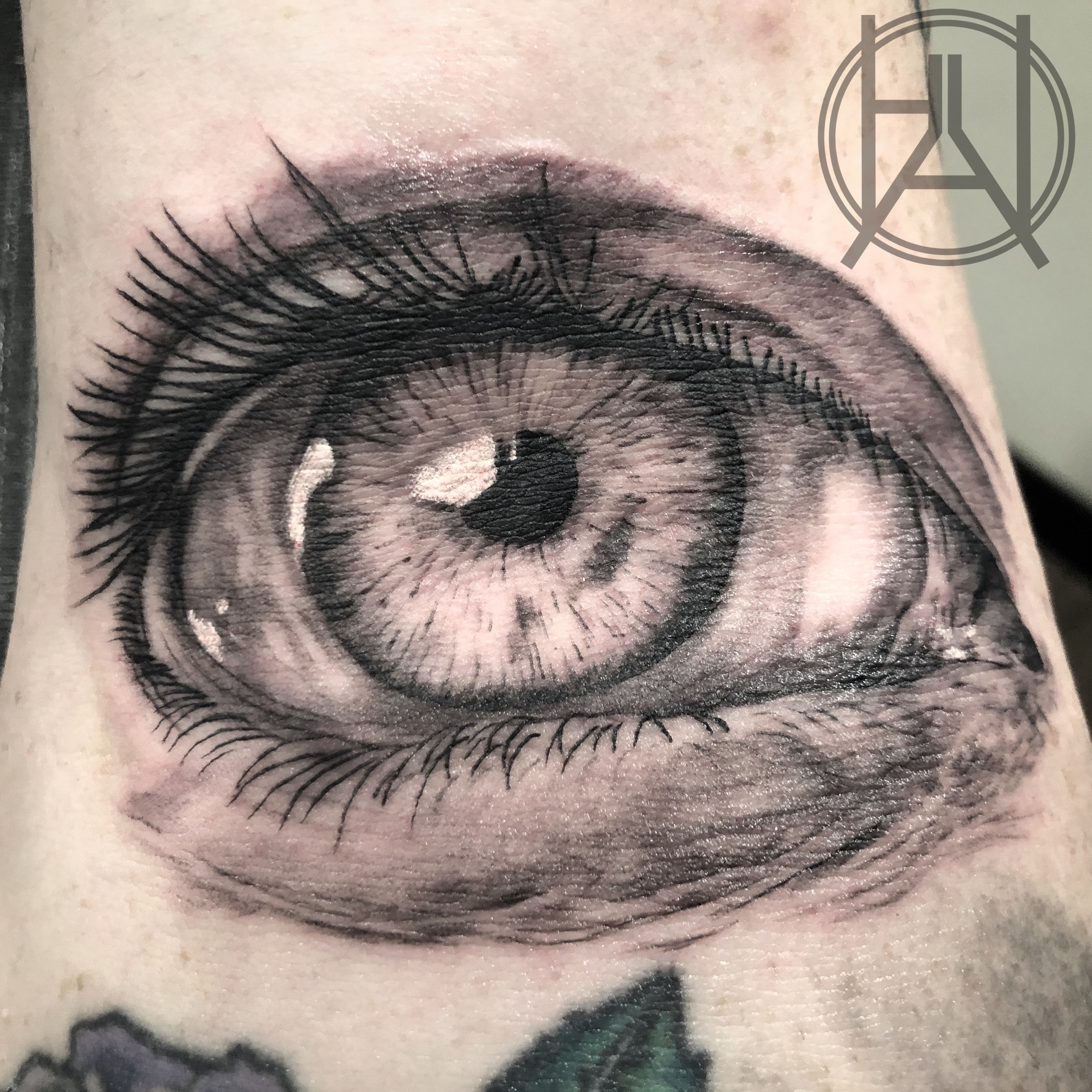 Hyper-realistic eyeball elbow ditch tattoo — black and grey
